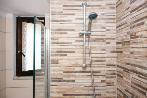a shower in a bathroom with a brick wall at Argo Rooms-Papadakis in Kissamos