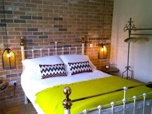 a bedroom with a bed with a brick wall at The Green Man Boutique Hotel in Takeley