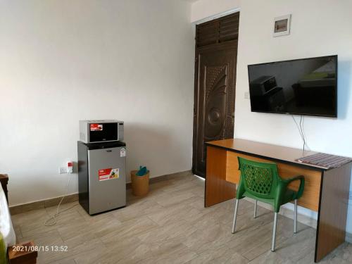 een kamer met een bureau, een televisie en een koelkast bij Mtwapa Pride Studio Apartment 33 in Mtwapa