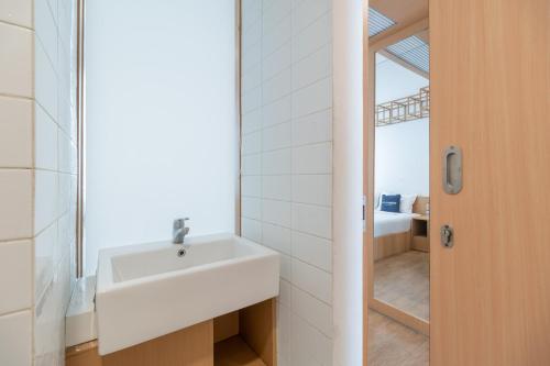 La salle de bains est pourvue d'un lavabo blanc et d'un miroir. dans l'établissement Urbanview Odori Residence Pondok Indah by RedDoorz, à Jakarta