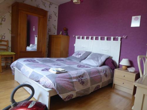 una camera con un letto con una parete viola di Chambres proches circuit a Le Mans