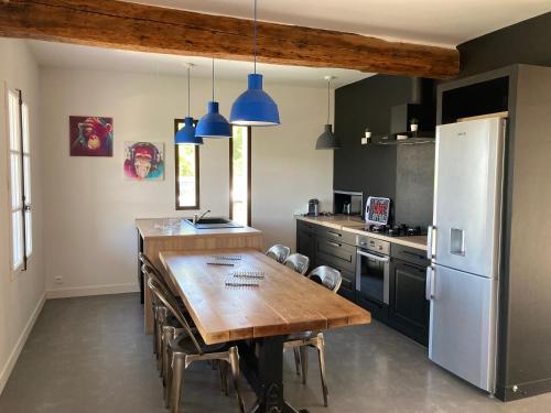 a kitchen with a wooden table and a refrigerator at La bastide in Malemort-du-Comtat