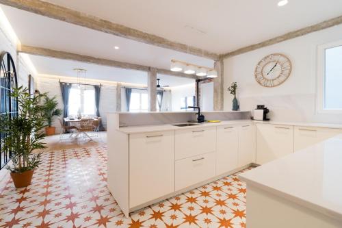 a kitchen with white cabinets and a clock on the wall at Amplio y moderno apartamento con tarima refrescante by Staynnapartments in Bilbao