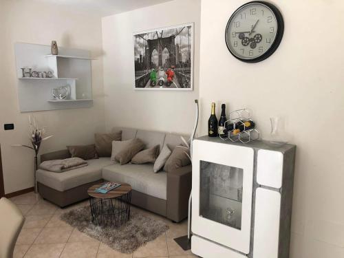 uma sala de estar com um sofá e um relógio na parede em Apartamento em Carpenedolo