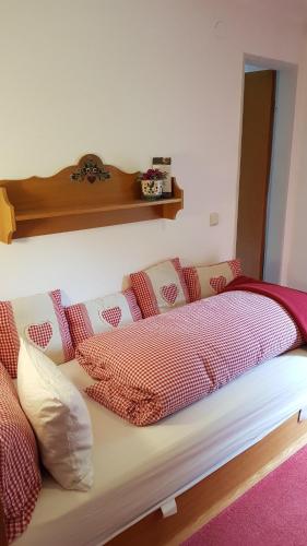 a bed with red and white pillows on it at Haus Guentli in Mittelberg