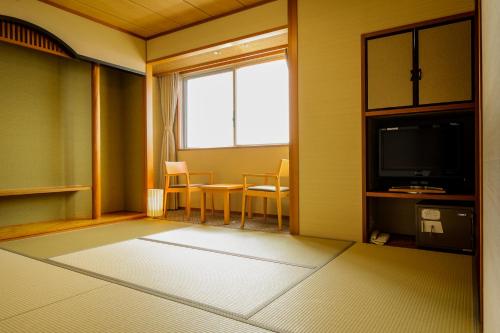 a room with a television and a table and chairs at KAMENOI HOTEL Genkainada in Kitakyushu