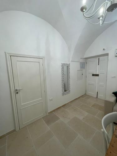a white room with two doors and a tile floor at Dimora L’Antico Bijou in Ostuni