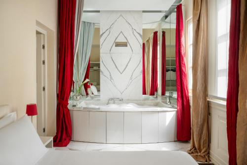 a bathroom with a white tub and red curtains at Ricasoli Firenze Luxury Apartments | UNA Esperienze in Florence