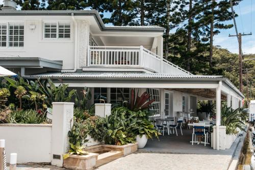 Dieses weiße Haus verfügt über einen Balkon mit einem Tisch und Stühlen. in der Unterkunft The Patonga Hotel in Patonga