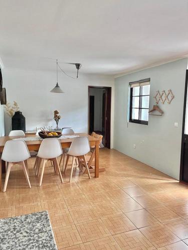 a dining room with a table and white chairs at Andorinha Levante in Grândola
