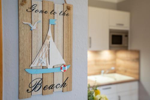a wooden sign with a sailboat on a wall in a kitchen at Landhaus Pönitz am See Wohnung 7 in Pönitz am See