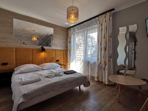 a bedroom with a bed and a table and a window at Willa Przystań in Jastarnia