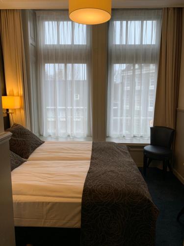 1 dormitorio con 1 cama, 1 silla y ventanas en Hotel Clemens, en Ámsterdam