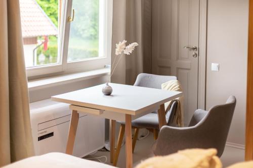 a white table and chairs in a room with a window at Nidos Banga in Nida