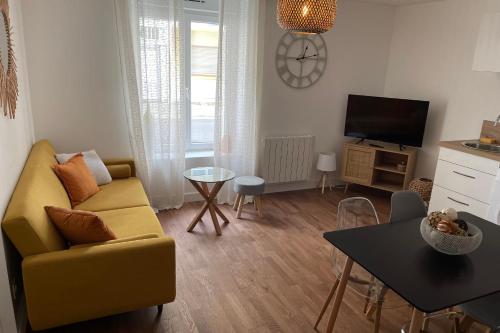 uma sala de estar com um sofá amarelo e uma mesa em LE POULORIO LOFT Studio RDC ByLocly em Lorient