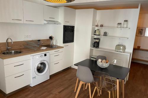 une cuisine avec une table et une machine à laver dans l'établissement LE POULORIO LOFT  Studio  RDC  ByLocly, à Lorient