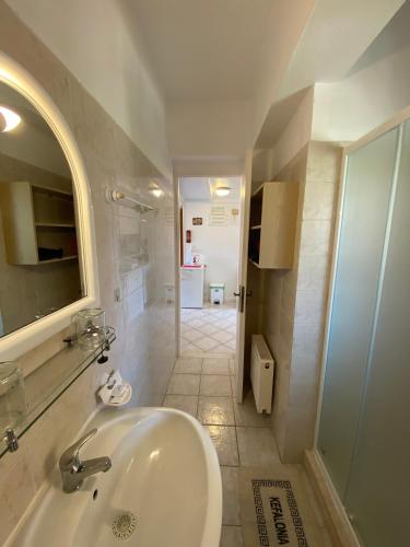 a white bathroom with a sink and a shower at Mariangela Apartments in Lixouri