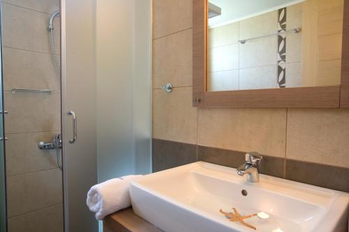 a bathroom with a sink and a mirror and a shower at Thalassa Mare Villas in Lygia
