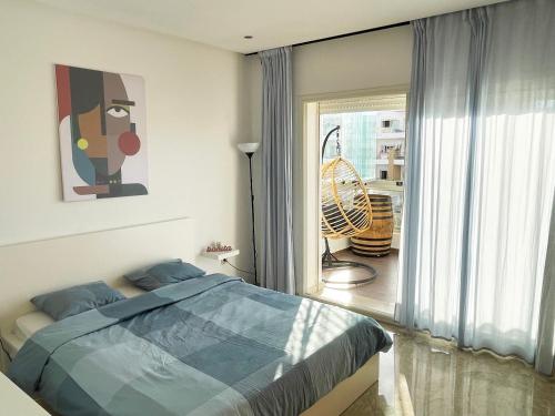 a bedroom with a bed and a large window at Peninsula Dar Bouazza Superbe appartement en résidence avec piscine activités in Dar Bouazza