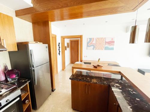 a kitchen with a refrigerator and a counter top at Peninsula Dar Bouazza Superbe appartement en résidence avec piscine activités in Dar Bouazza