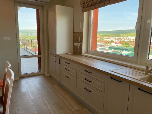 a kitchen with a sink and two large windows at Fortuna Panorama Apartman in Odorheiu Secuiesc