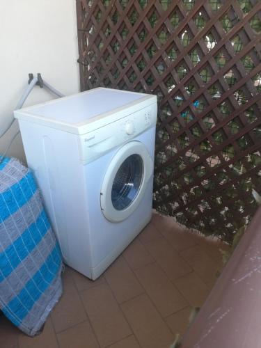a white washing machine sitting next to a fence at Appartamenti Scilla Paese Albergo in Scilla