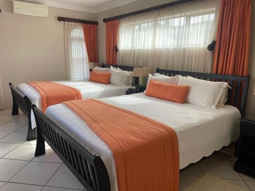 two beds in a hotel room with orange curtains at Trevi Sea-view Apartment in Margate