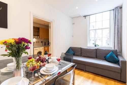 a living room with a couch and a table with flowers at Mansion House Apartments in London
