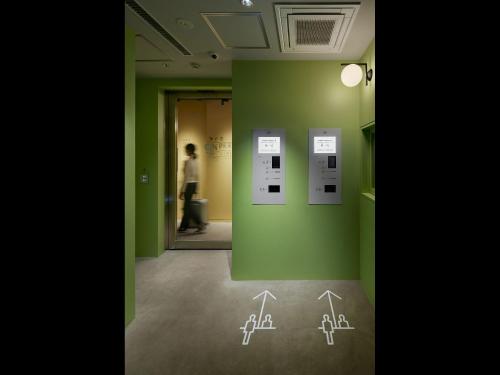um quarto com paredes verdes e desenhos na parede em 9h nine hours woman Shinjuku em Tóquio