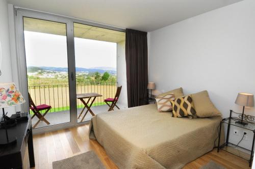 a bedroom with a bed and a balcony with a view at Quinta Pedras De Baixo in Longos