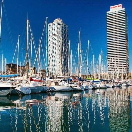 un grupo de barcos atracados en un puerto con edificios en Swan, en Barcelona