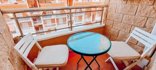 a balcony with two chairs and a glass table and chairs at TORRE La MATA Apartamento in La Mata