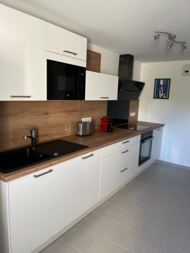 une cuisine avec des armoires blanches et un évier dans l'établissement l'Amont et l'Aval, à Étretat