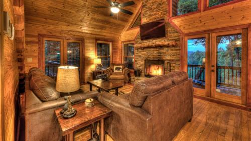 a living room with leather furniture and a fireplace in a log cabin at Aska Retreat in Blue Ridge