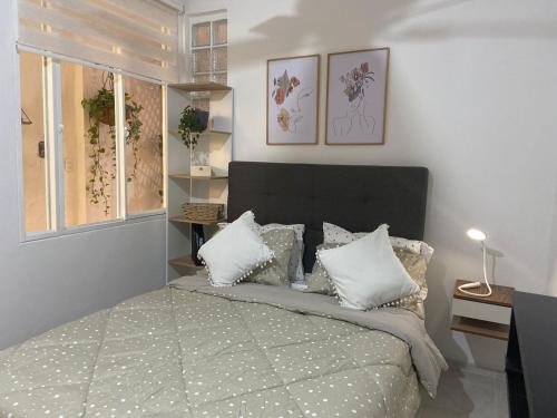 1 dormitorio con 1 cama grande con almohadas blancas en Mercanti Apts Caney, en Cali