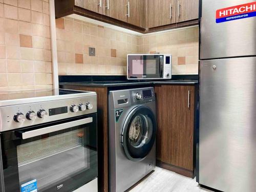 a kitchen with a washing machine and a microwave at Cozy Upgraded Residential Flat with sea, Mangrove, pool view - 1203 Not Hotel in Abu Dhabi