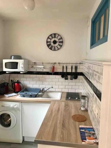 une cuisine avec un évier et une horloge murale dans l'établissement Studio proche des falaises, du port et des plages, au Tréport