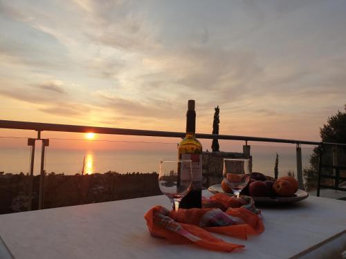a bottle of wine and glasses on a table with the sunset at Lavender House 1 - Agios Nikitas in Agios Nikitas