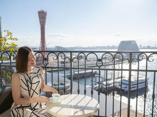 a woman sitting at a table with a cup of coffee at Hotel La Suite Kobe Harborland in Kobe