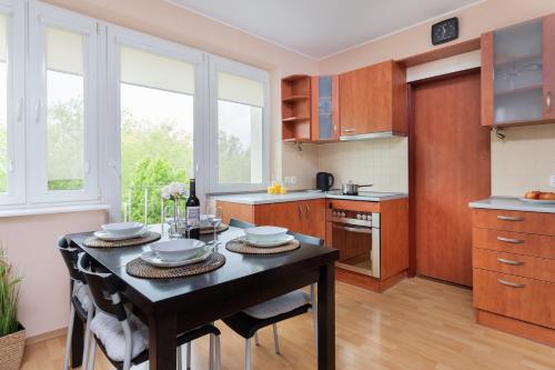 a kitchen with a table and chairs and windows at Gdansk Zabianka Sztormowa Apartment with 1 Bedroom by Renters in Gdańsk