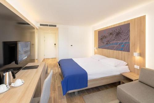 a hotel room with a bed and a tv at Medora Auri Family Beach Resort in Podgora