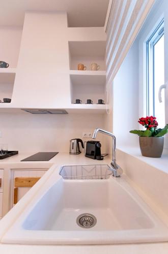 a white kitchen with a sink and a window at Juliano luxury apartments, port of Naxos in Naxos Chora