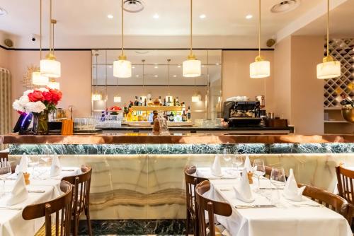 un restaurant avec des tables et des chaises blanches et un bar dans l'établissement Hôtel Chateaubriand, à Paris