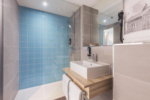 a bathroom with a white sink and blue tiles at the niu Yen in Hamburg