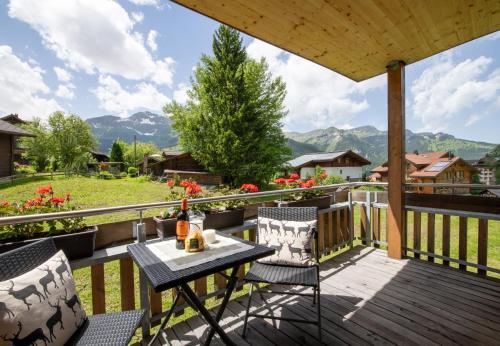 a patio with a table and chairs on a deck at Chalet Stella Duplex Penthouse in Wengen