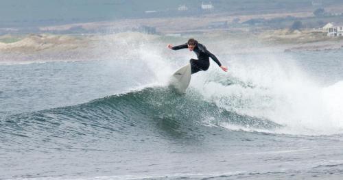 a man riding a wave on a surfboard in the ocean at Ferryview B&B V23 X577 in Cahersiveen