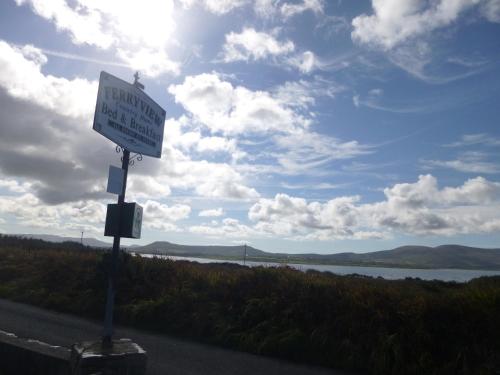 a sign on the side of a road next to a lake at Ferryview B&B V23 X577 in Cahersiveen