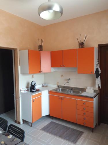 una cucina con armadi arancioni e lavandino di House & Garden a Marina di Massa