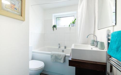 諾里奇的住宿－Bright 3 bedroom townhouse near city centre，浴室配有白色浴缸、卫生间和水槽。