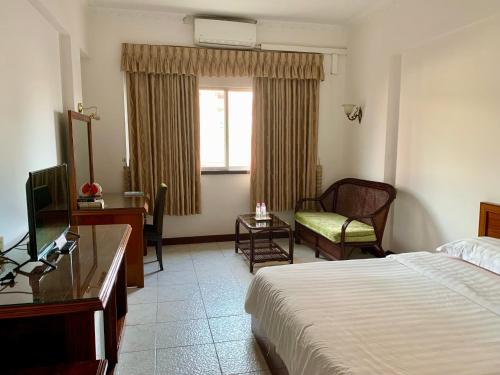a hotel room with a bed and a desk and a window at Chung Hsin Hotel 中信酒店 in Phnom Penh